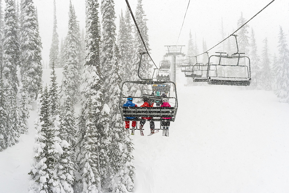 Skiers on a chairlift at Sun Peaks ski resort during a snowfall, Kamloops, British Columbia, Canada