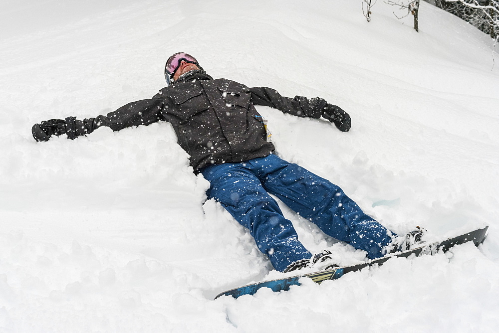 Snowboarder lying in the snow at Sun Peaks Resort, Kamloops, British Columbia, Canada