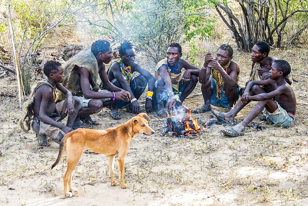 Hadzabe hunters and their dog gather around a campfire after a successful morning hunt near Lake Eyasi, Tanzania