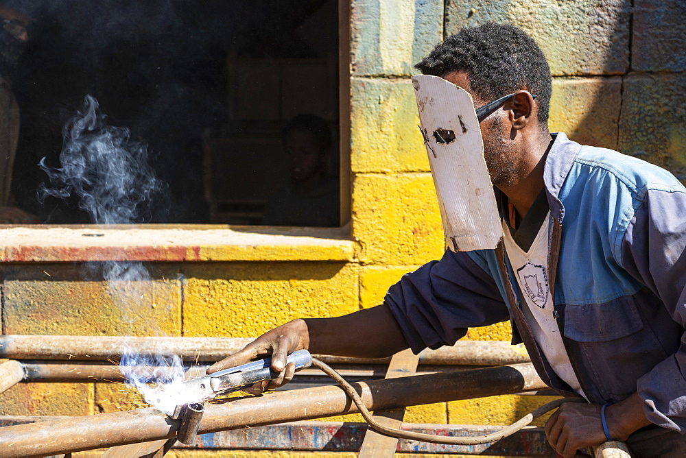 Welder at the Medeber Market, where artisans recycle old tyres and tins to make new artifacts, Asmara, Central Region, Eritrea