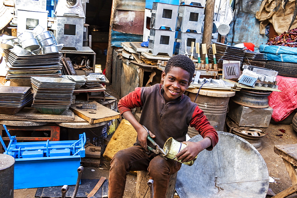 Eritrean boy cutting a can at the Medeber Market, where artisans recycle old tyres and tins to make new artifacts, Asmara, Central Region, Eritrea