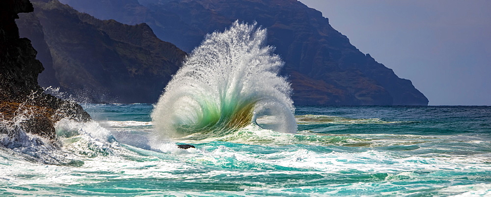 Large ocean wave crashes into rock along the Na Pali Coast, Kauai, Hawaii, United States of America