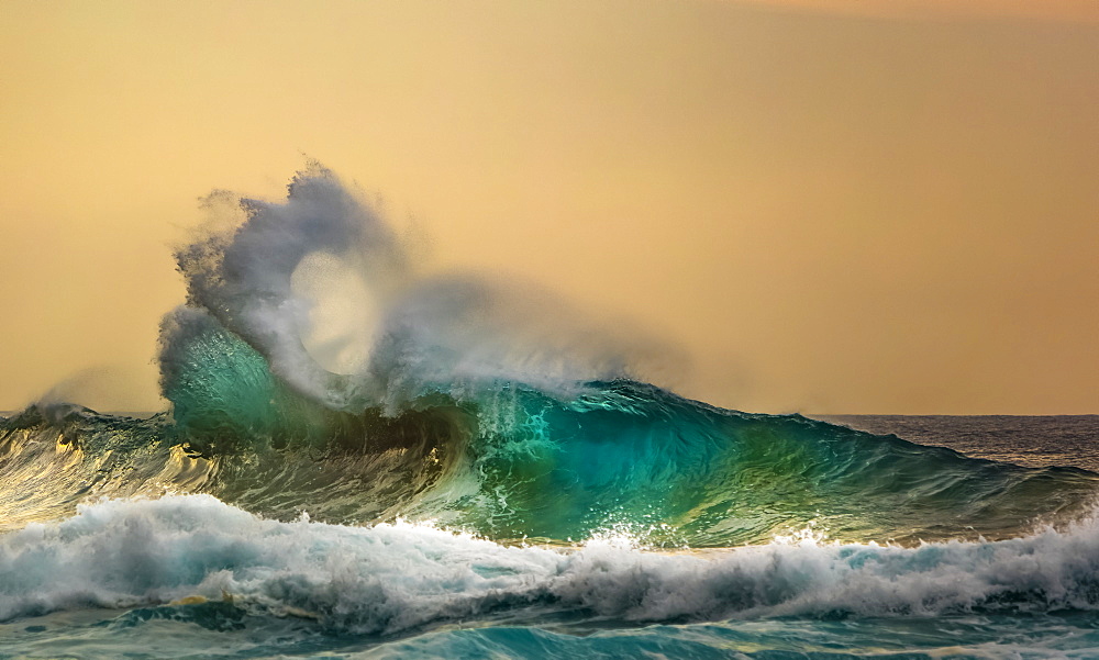 Ocean waves crashing into the shore off the Na Pali coast at sunset, Kauai, Hawaii, United States of America