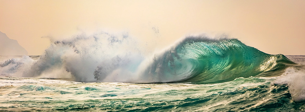 Ocean waves crashing into the shore off the Na Pali coast at sunset, Kauai, Hawaii, United States of America