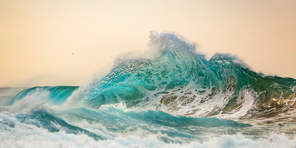 Ocean waves crashing into the shore off the Na Pali coast at sunset, Kauai, Hawaii, United States of America