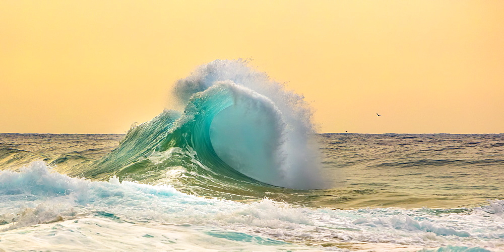 Ocean waves crashing into the shore off the Na Pali coast at sunset, Kauai, Hawaii, United States of America