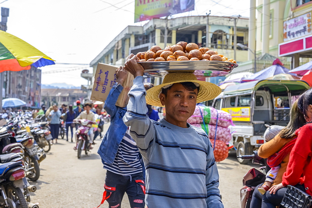 Young man carrying food on his head in the busy street, Lashio, Shan State, Myanmar