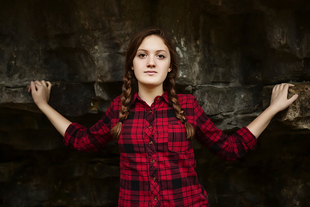 A girl standing in front of a rock wall looking at the camera, Toronto, Ontario, Canada