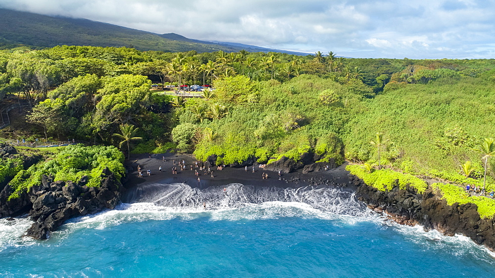 Tourists on the black sand beach at Waianapanapa State Park, Hana, Maui, Hawaii, United States of America