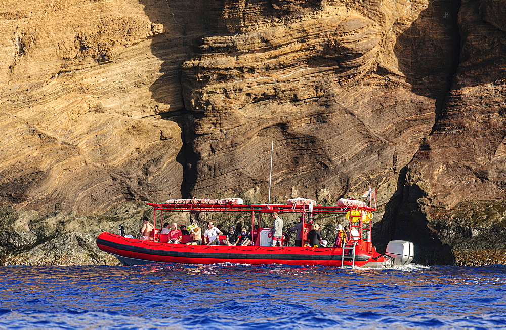 Snorkelers getting ready to enter the water from a snorkelling tour boat operated out of Maui, Hawaii. They are located next to the backwall of Molokini Crater which is a volcanic tuff cone, Maui, Hawaii, United States of America