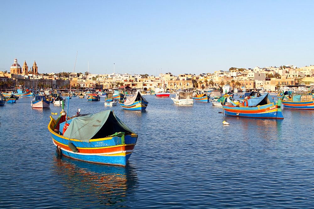 Multi-coloured fishing boats and town, St. Julians, Malta, Mediterranean, Europe