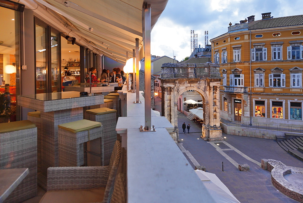 High angle view from a bar of the Roman triumphal arch, Arch of Sergil in the old town at dusk, Pula, Istria, Croatia, Europe