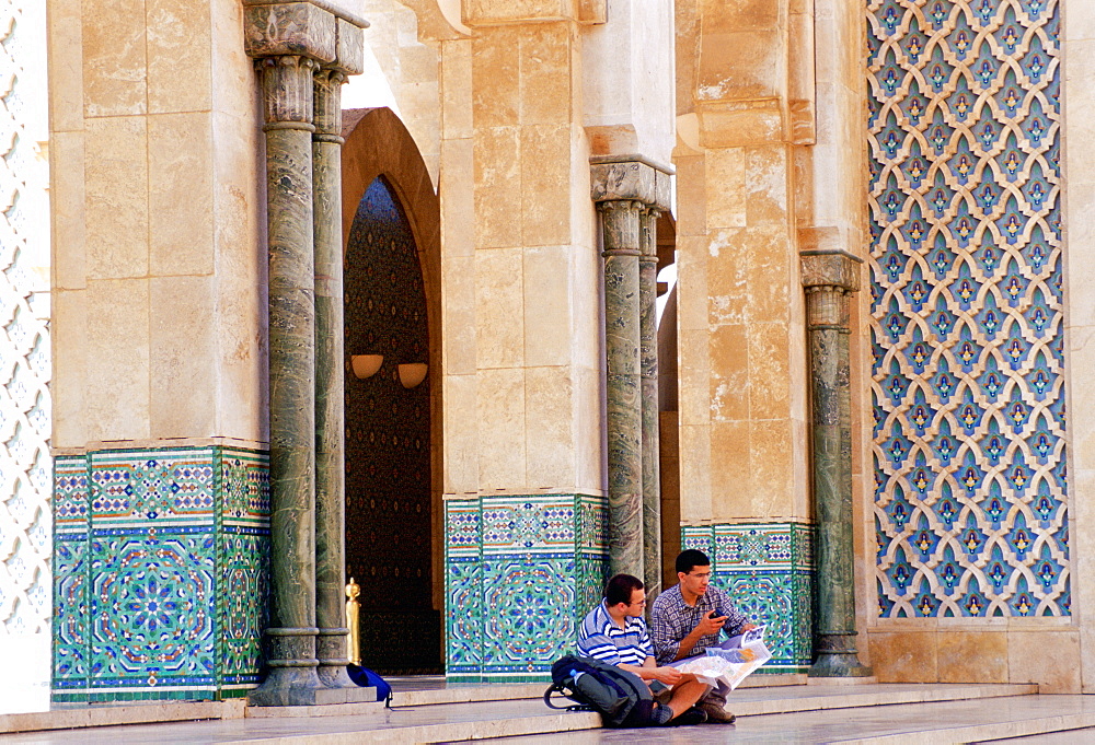 Tourists sitting on the steps of King  Hassan II Mosque in Casablanca, Morocco