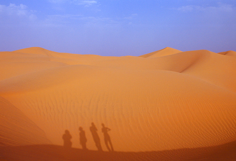 Tourists climbing up a sand dune in the Sahara Desert, Morocco