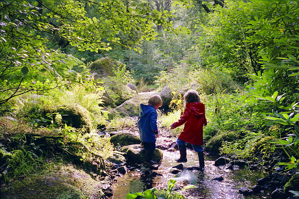 A four year old boy and five year old girl playing in a stream in Devon