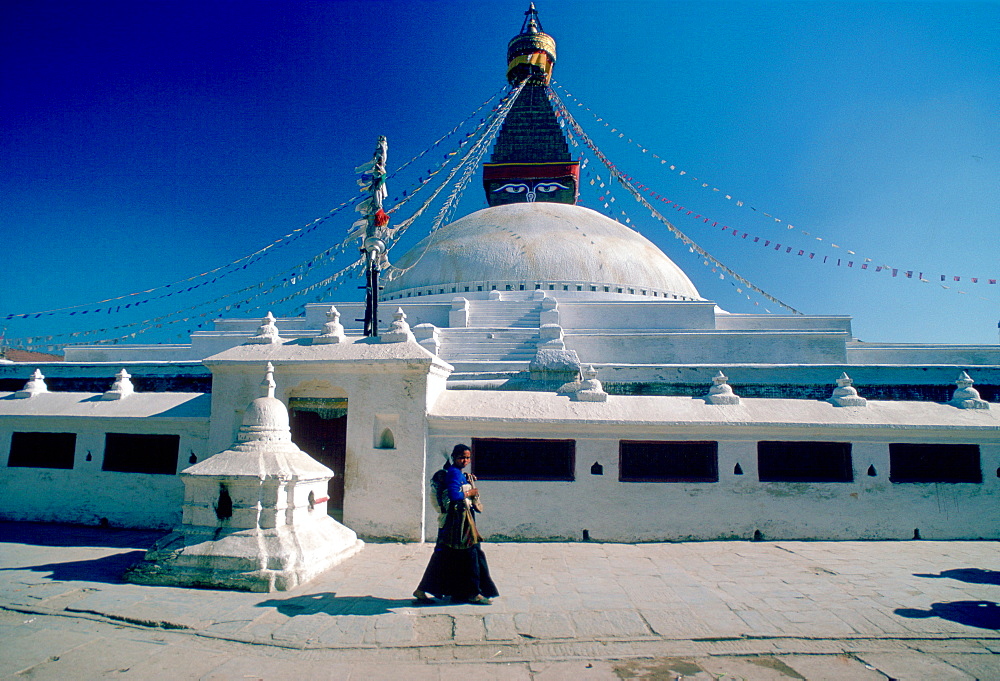 Nepalese woman walking past Bouddhanath Stupa in Nepal at the Kathmandu Valley World Heritage Site.