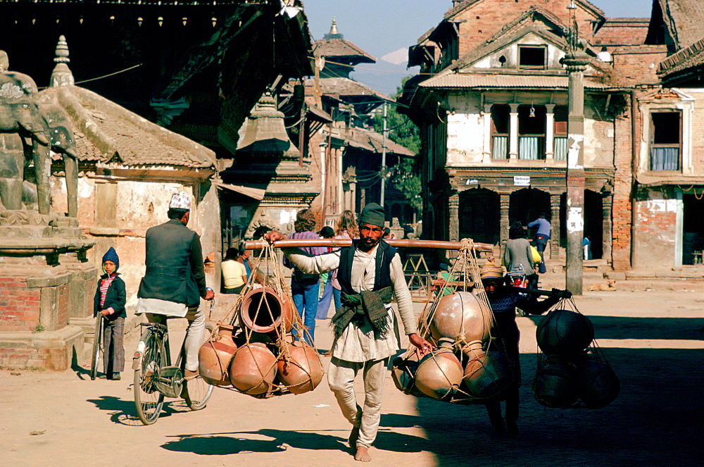 Man carrying heavy pots on shoulder hoist, Patan, Nepal