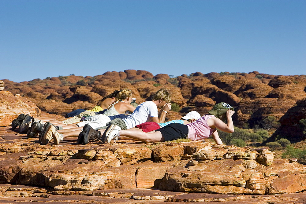 Tourists lie down to photograph King's Canyon, Red Centre, Northern Australia