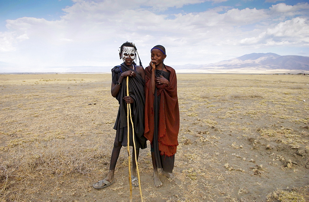 Young recently circumcised Masai Warriors (moran) with traditional face paint after 'coming of age' and a young Masai girl in the Serengei Plains, Tanzania.