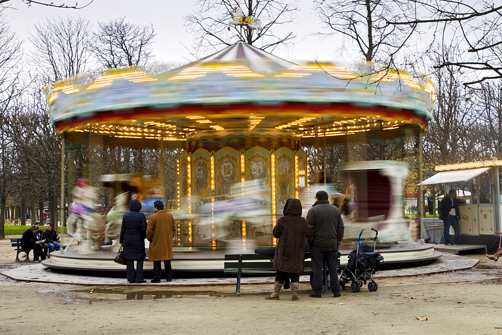 Parents watch their children on the carousel in Jardin des Tuileries, Central Paris, France