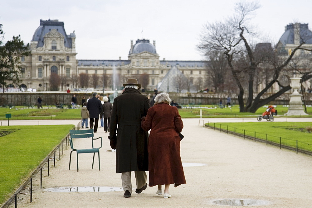 Elderly couple take a calm stroll arm in arm through Jardin des Tuileries by the Louvre Museum art gallery, Central Paris, France