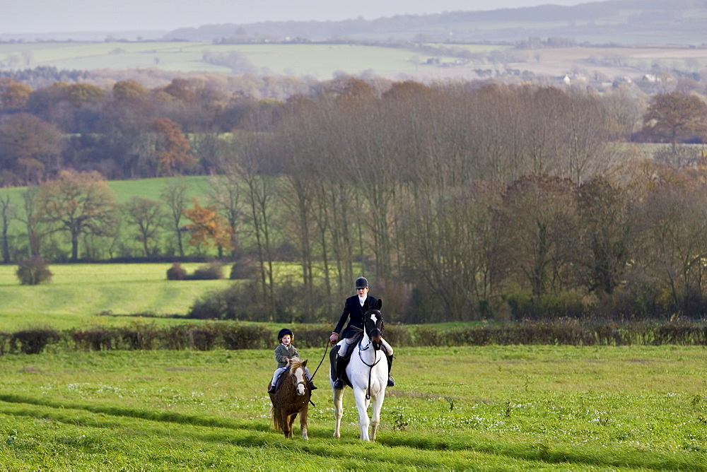 Mother and daughter ride together in rolling hillside, The Cotswolds, Oxfordshire, United Kingdom