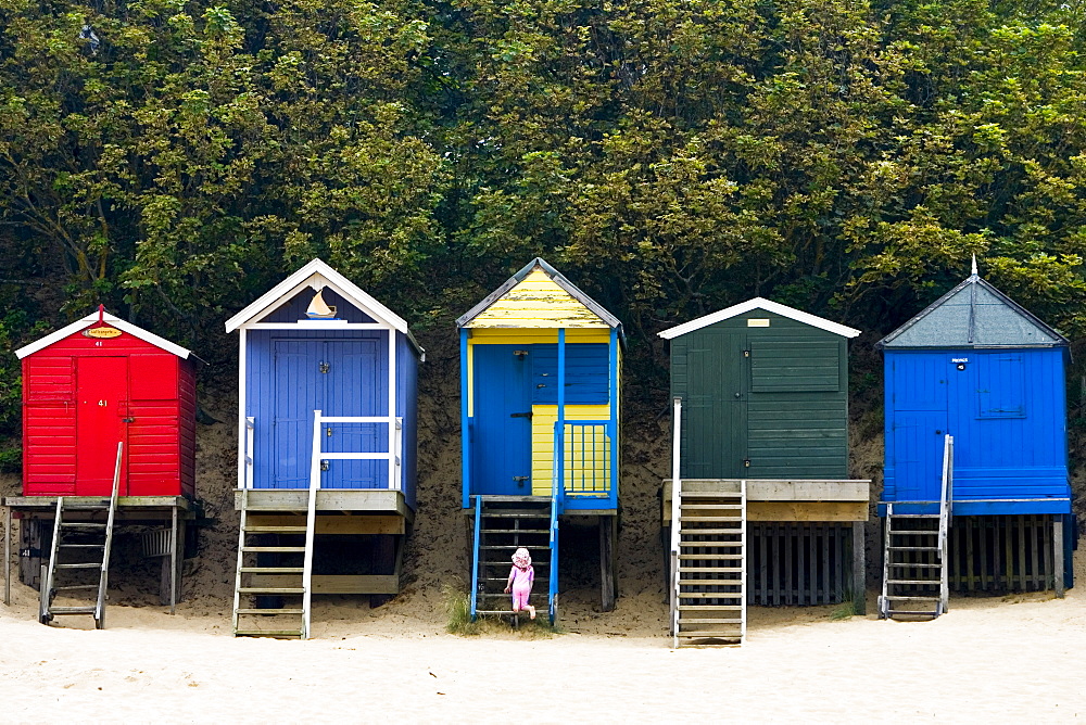 Young girl explores beach huts in Wells-Next-The-Sea, Norfolk, United Kingdom