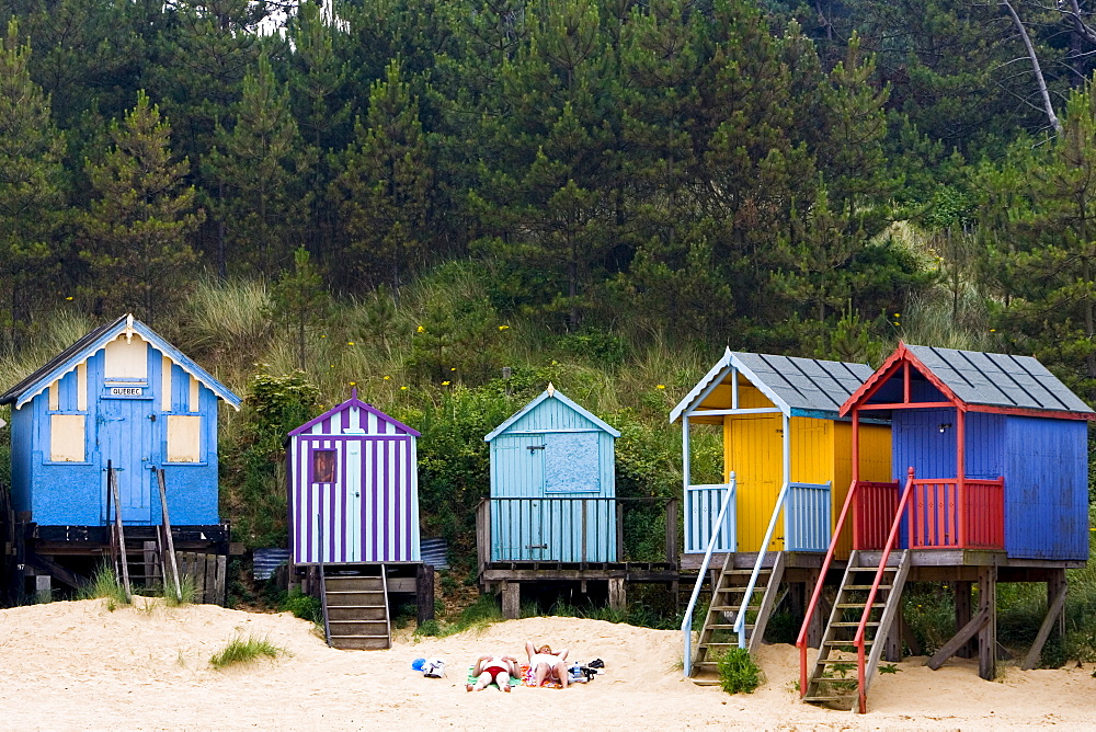 Couple sunbathe outside their beach hut in Wells-Next-The-Sea, Norfolk, United Kingdom