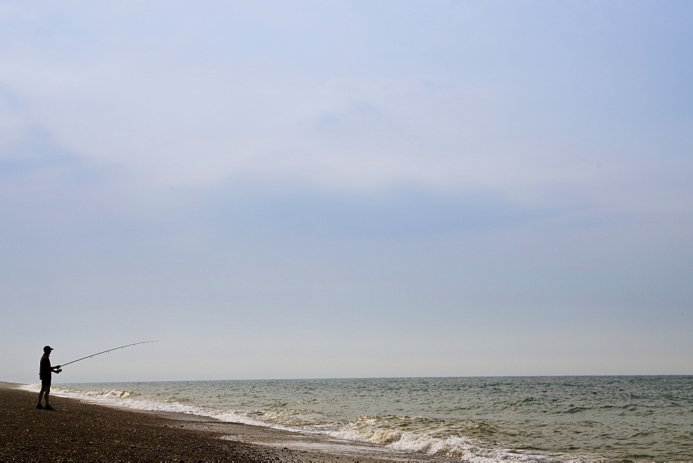 Man fishing on Cley Beach, Norfolk, United Kingdom