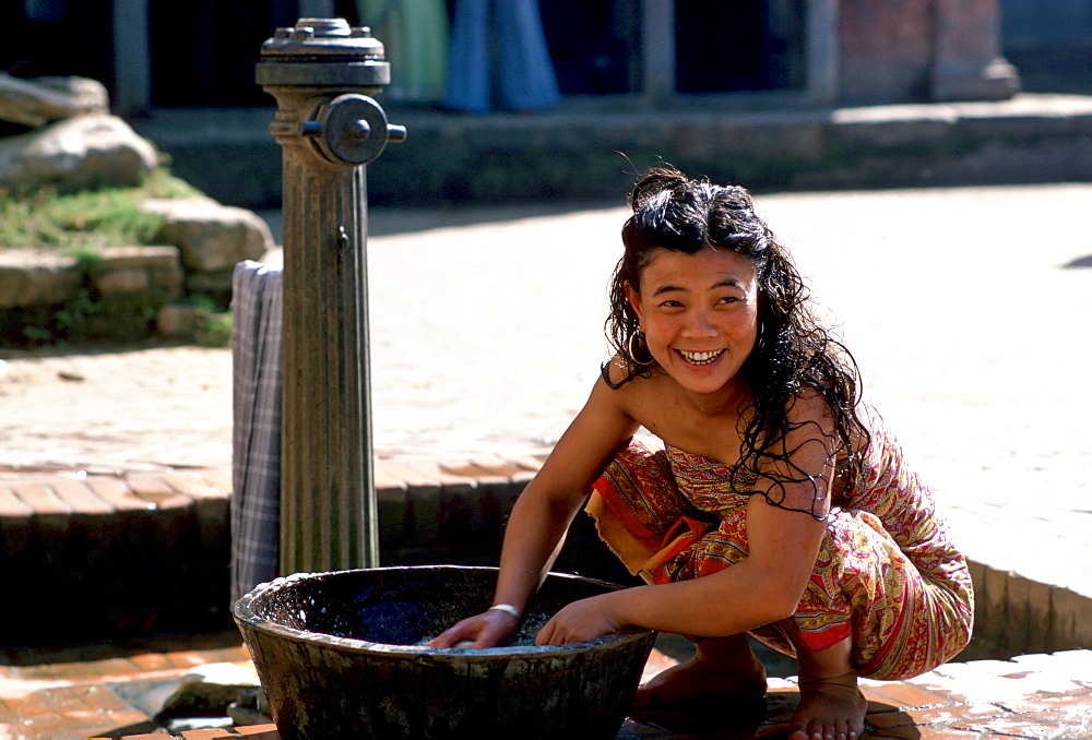 Young woman washing at water pump, Patan, Nepal