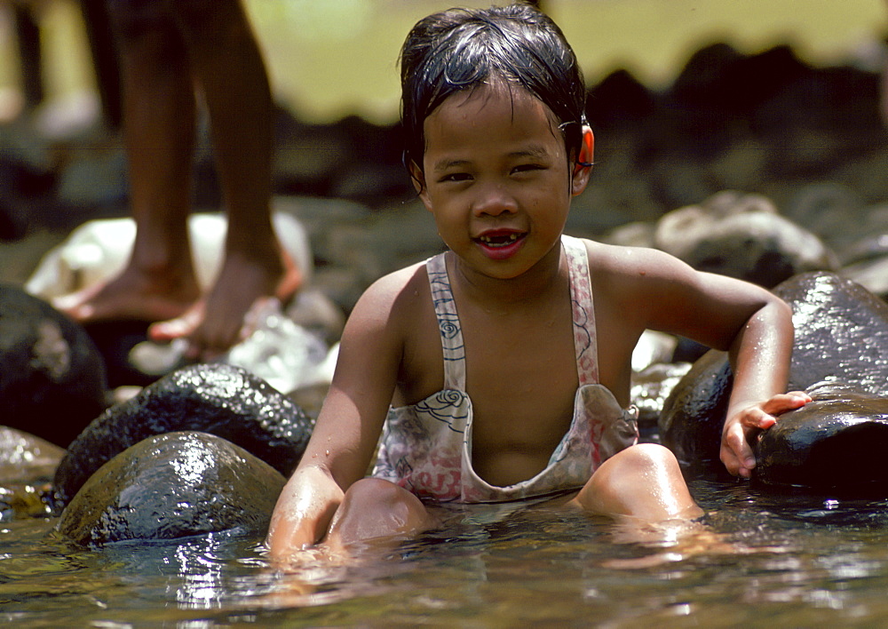 A young child washing in a river in the Philippines