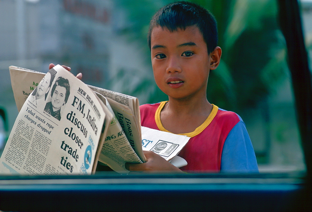 Boy sells newspapers at car windows in Manila, Philippines