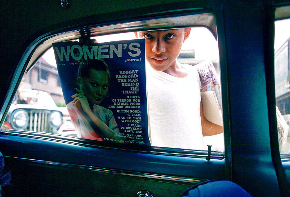 Boy sells magazines at car windows in Manila, Philippines