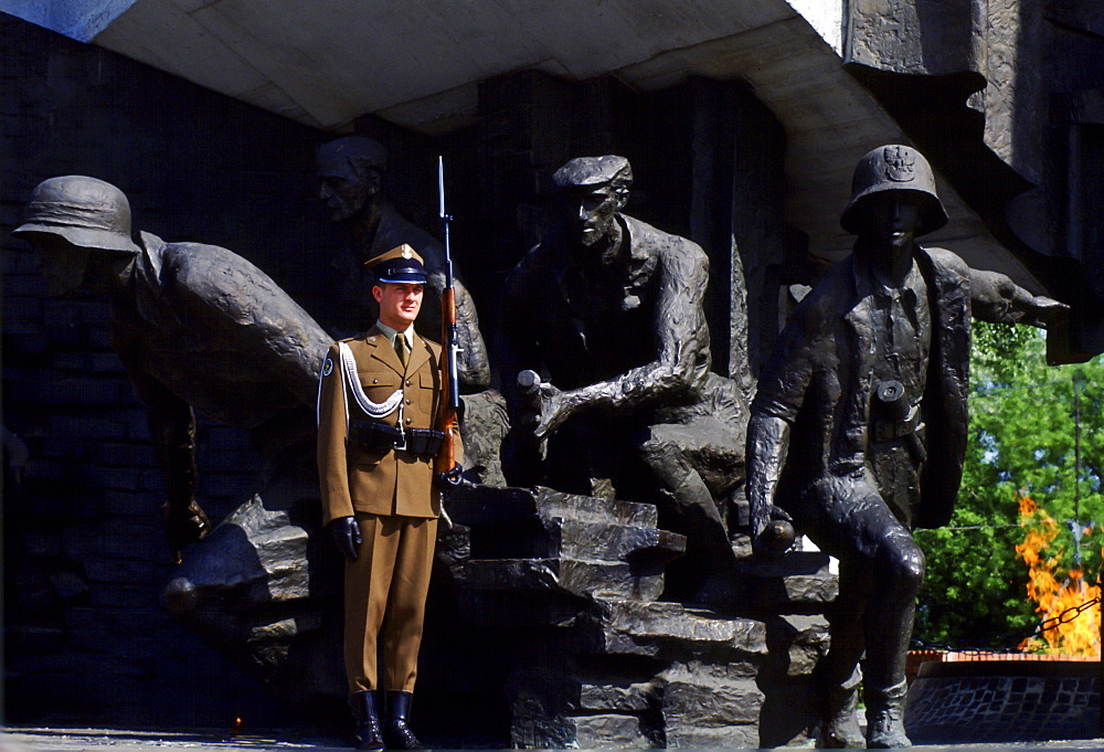 Soldier stands at attention with a rifle to guard the Warsaw Uprising Monument in Poland.