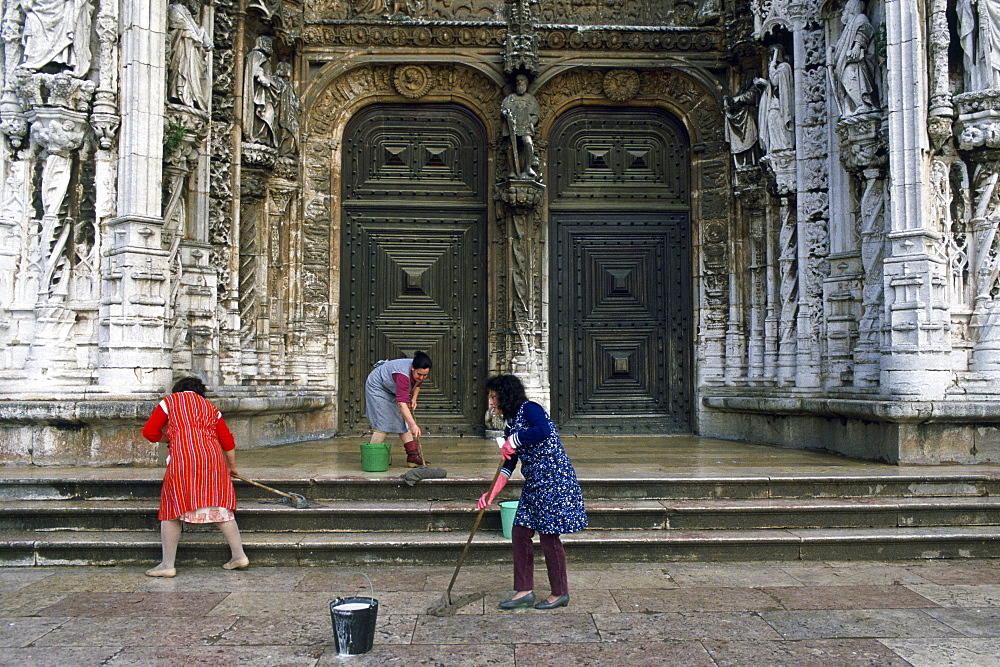 Women cleaning the steps outside a church in Lisbon, Portugal.