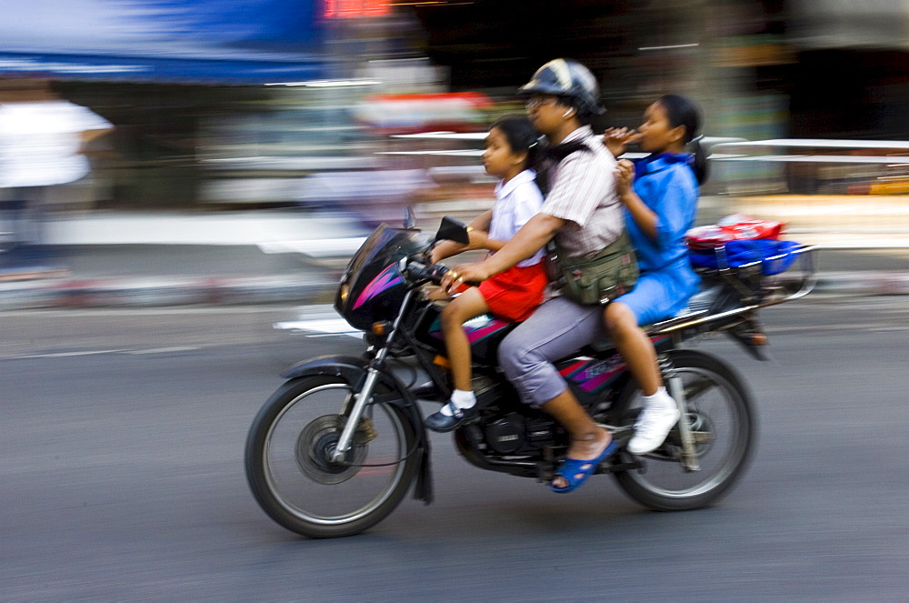 Commuter and his children travel on a motorbike, Bangkok, Thailand