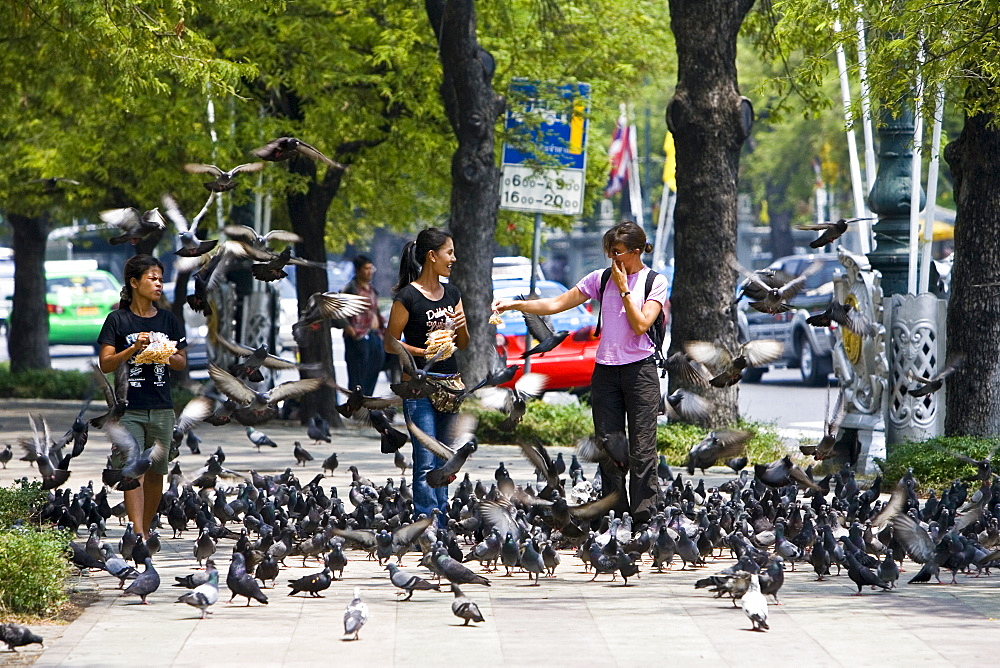 Women sell bags of bird seed to tourists on the streets of Bangkok, Thailand