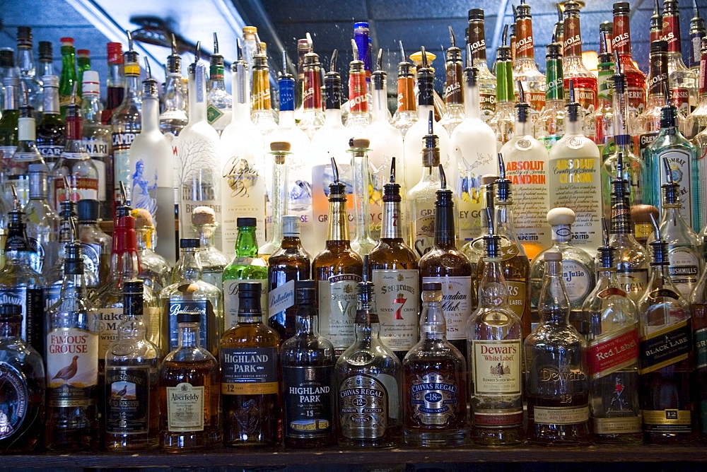 Whiskey and spirit bottles lined up along bar, Georgetown, Washington DC, USA