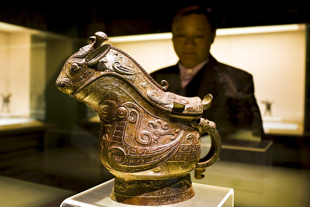 Man looks at Fu Yi Gong wine vessel on display in glass case at the Shanghai Museum, China