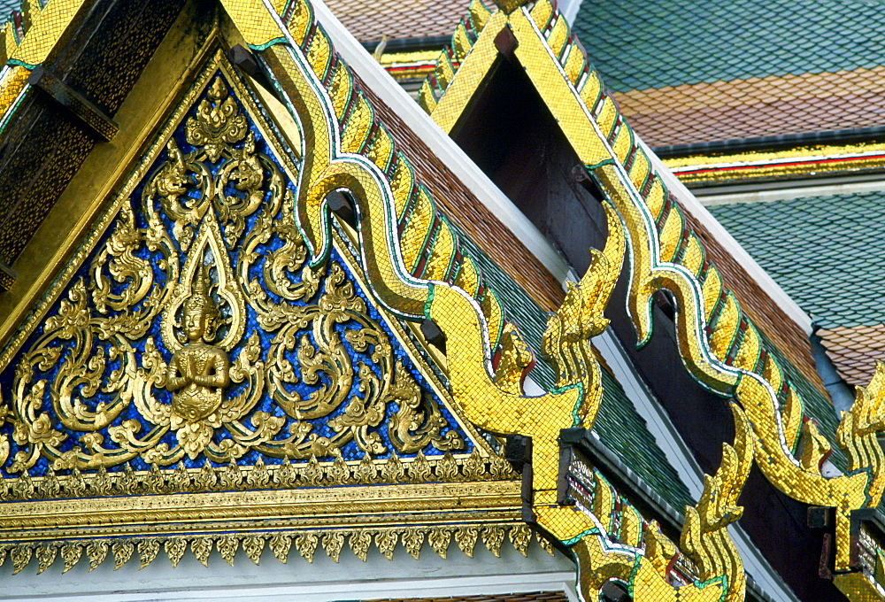 Detail of the ornate gilded woodcarving and roof tiling on the Grand Palace in Bangkok, Thailand.