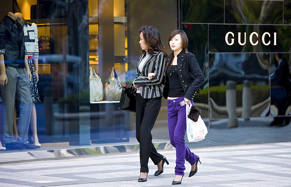 Women outside Gucci deisgner clothes shop, on Nanjing Road, central Shanghai, China