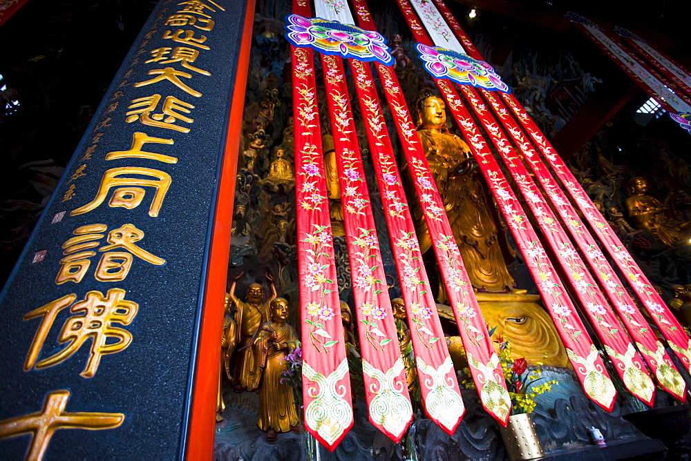 Golden Buddha and silk banners in the Grand Hall of Magnificence of the Jade Buddha Temple, Shanghai, China