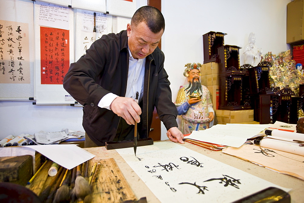 Skilled Chinese calligrapher at work in gift shop of the Jade Buddha Temple, Shanghai, China