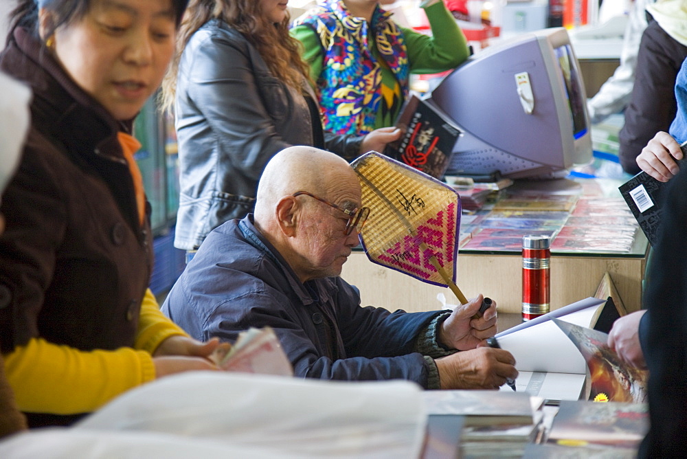 Mr Yang Peiyan, the farmer who found the Terracotta Warriors, signs books in the gift shop at Qin Museum, Xian