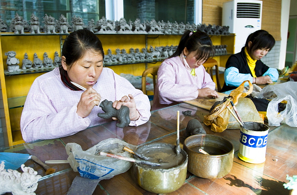 Women make clay figure souvenirs in factory, Xian, China