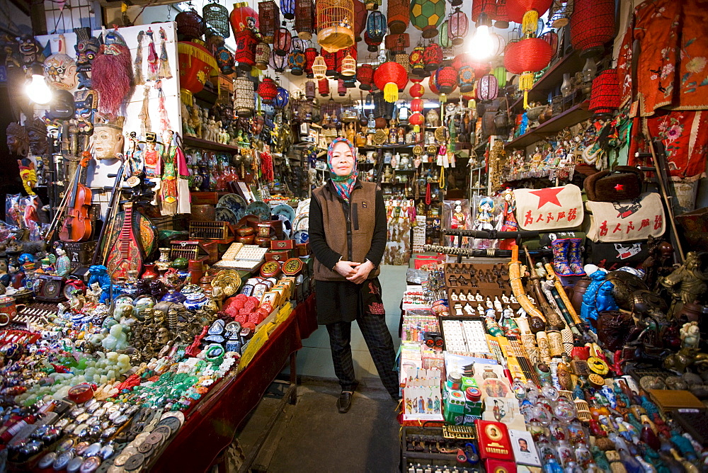 Chinese woman of Hui Minority Group selling souvenirs at market stall in Moslem district of Xian, China