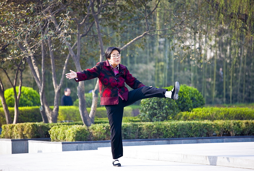 Woman practises Tai chi as part of her morning exercise in the park by the City Wall of Xian, China