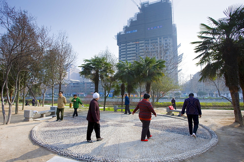 People walk in a circle as part of their morning exercise in the park by the City Wall of Xian, China