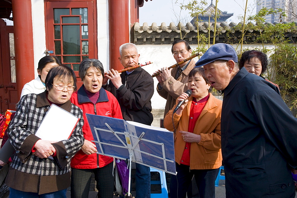 People gather to form an informal choir, part of the morning exercise in the park by the City Wall, Xian, China