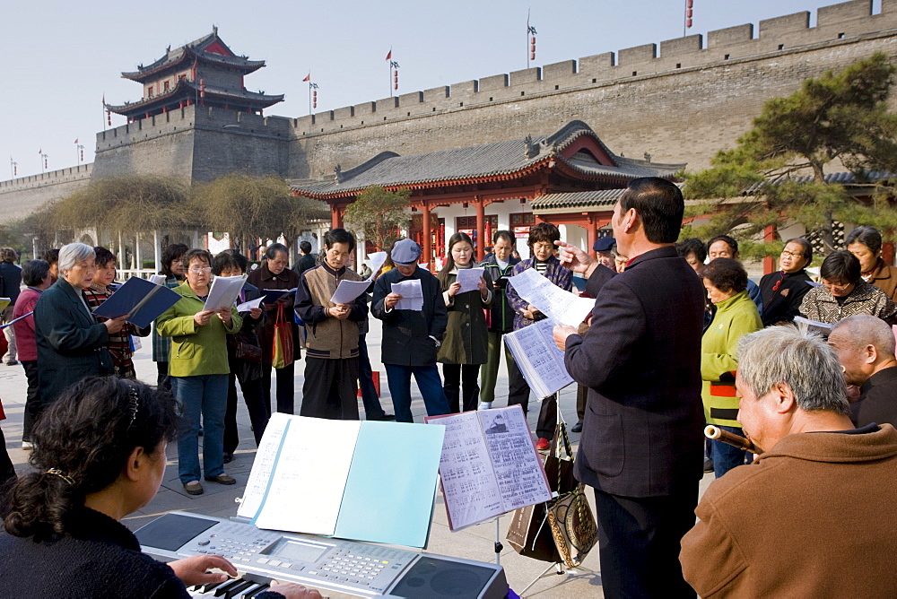 People gather to form an informal choir, part of the morning exercise in the park by the City Wall, Xian, China